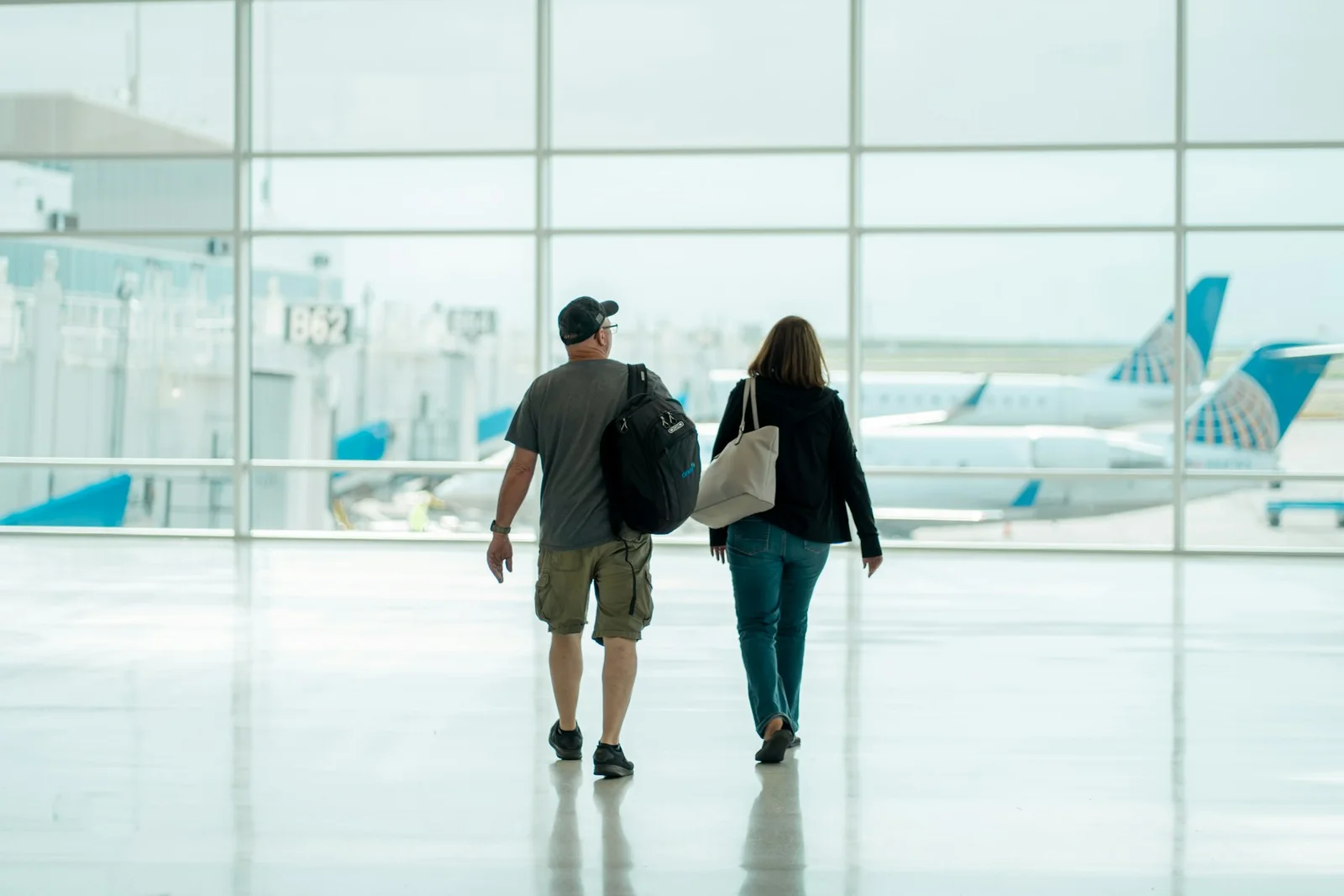 공항 터미널을 걸어가는 두 여행자
